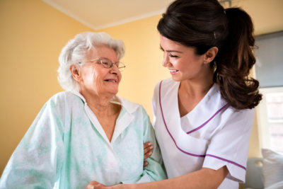 an old lady and a nurse smiling at each other