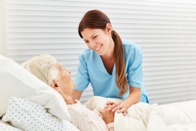 woman smiling at a senior in bed