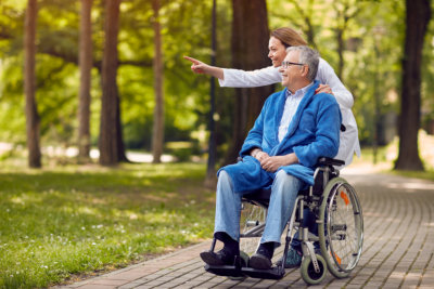 a caretaker and a man on a wheel chair in the park