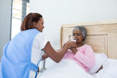 a nurse helping an elderly drink water