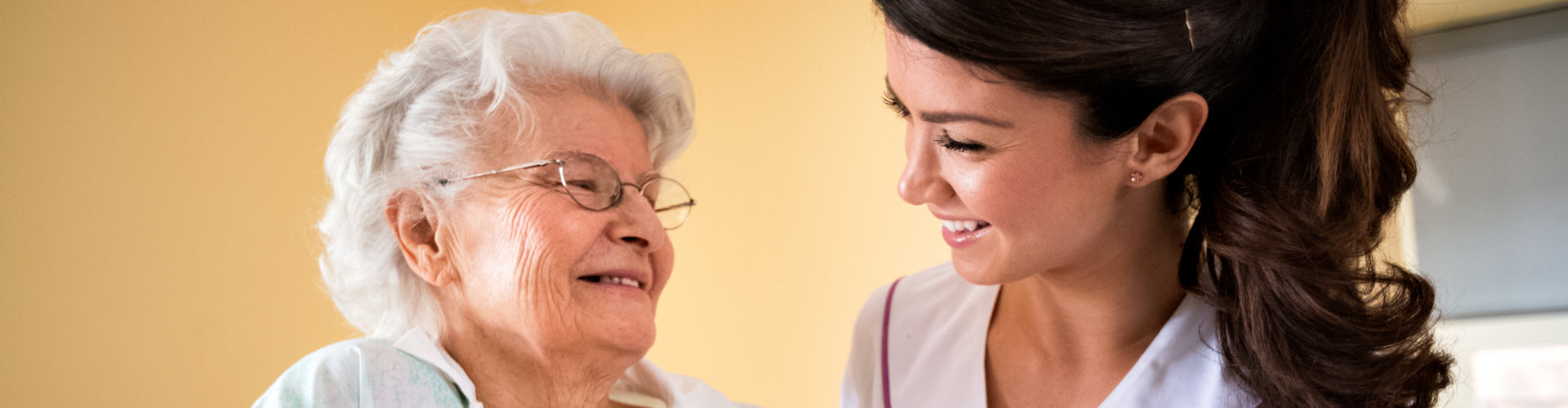 an old lady and a nurse smiling at each other