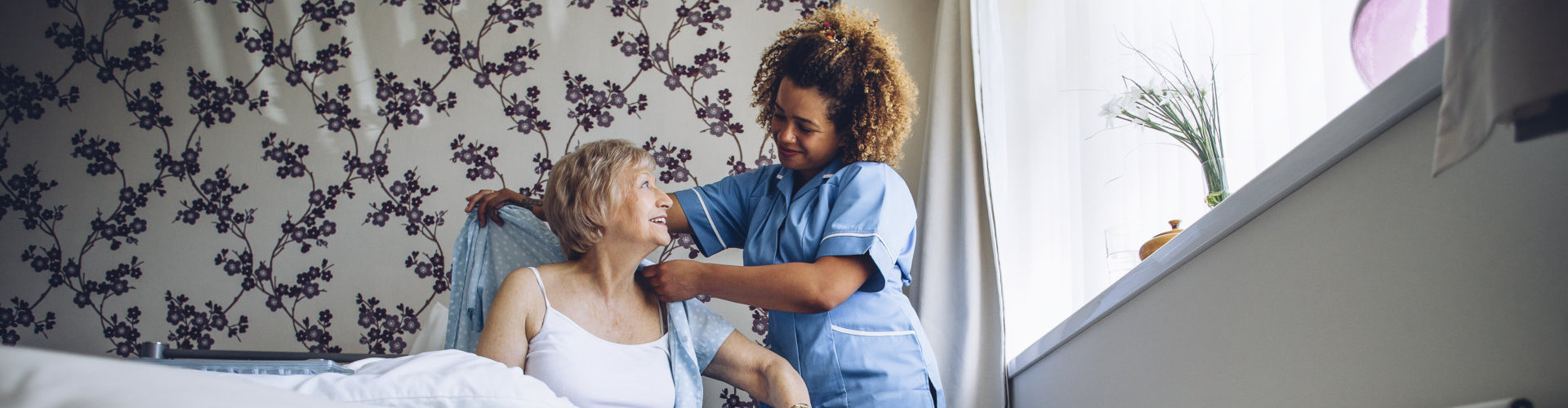 a nurse giving an old lady a blanket